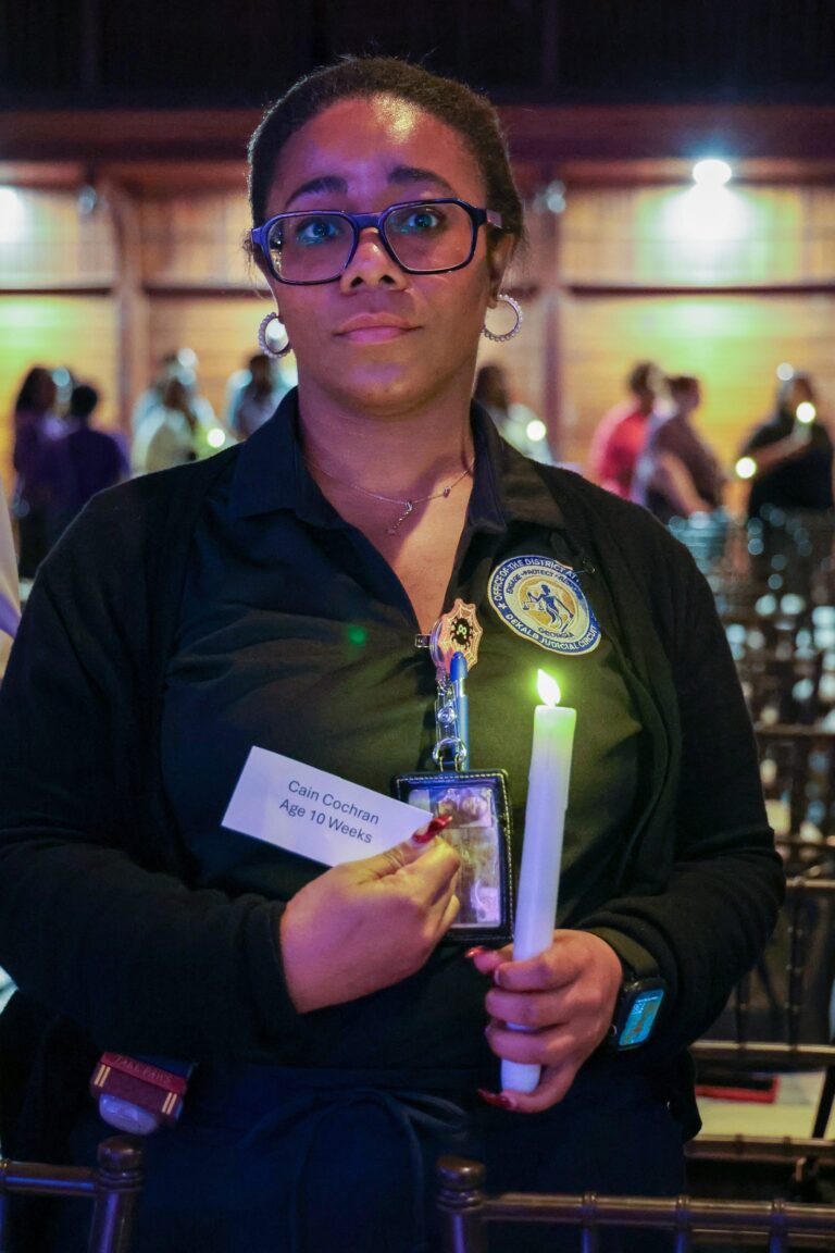 An attendee holds a candle and a memorial card