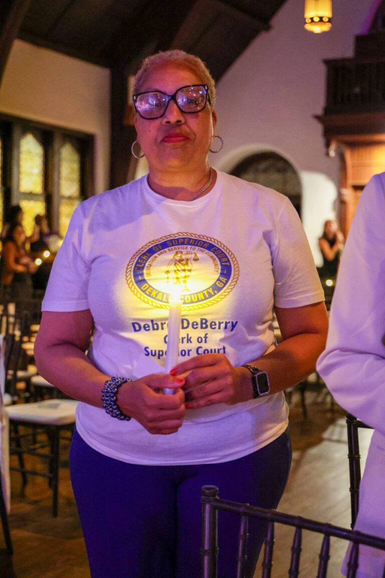 An attendee in a commemorative shirt holds a candle