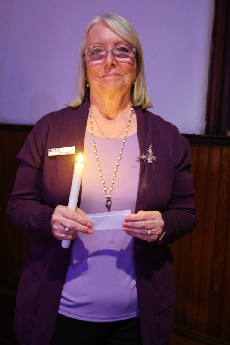 An attendee holds a candle and a memorial card