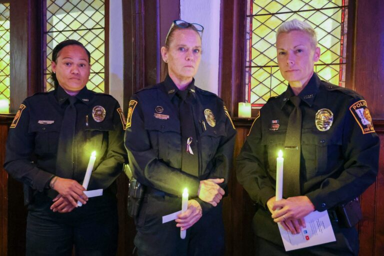 Three officers hold lit candles