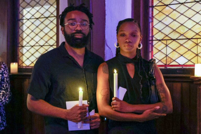 Two attendees hold lit candles