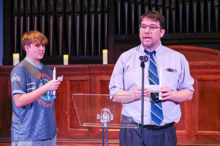 A speaker and a young man stand together at the lectern