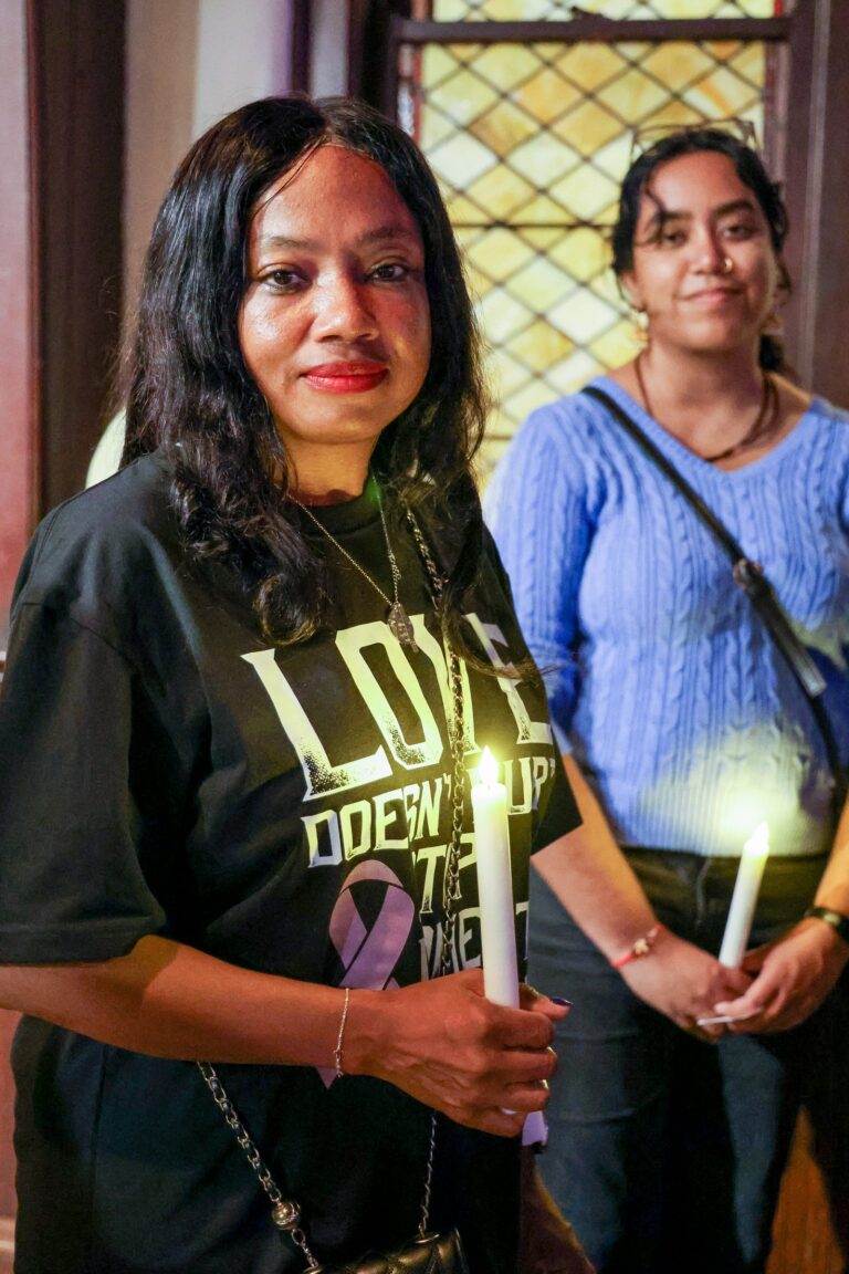 Two attendees hold lit candles in the sanctuary