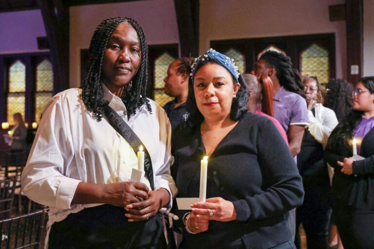 Attendees stand together holding candles