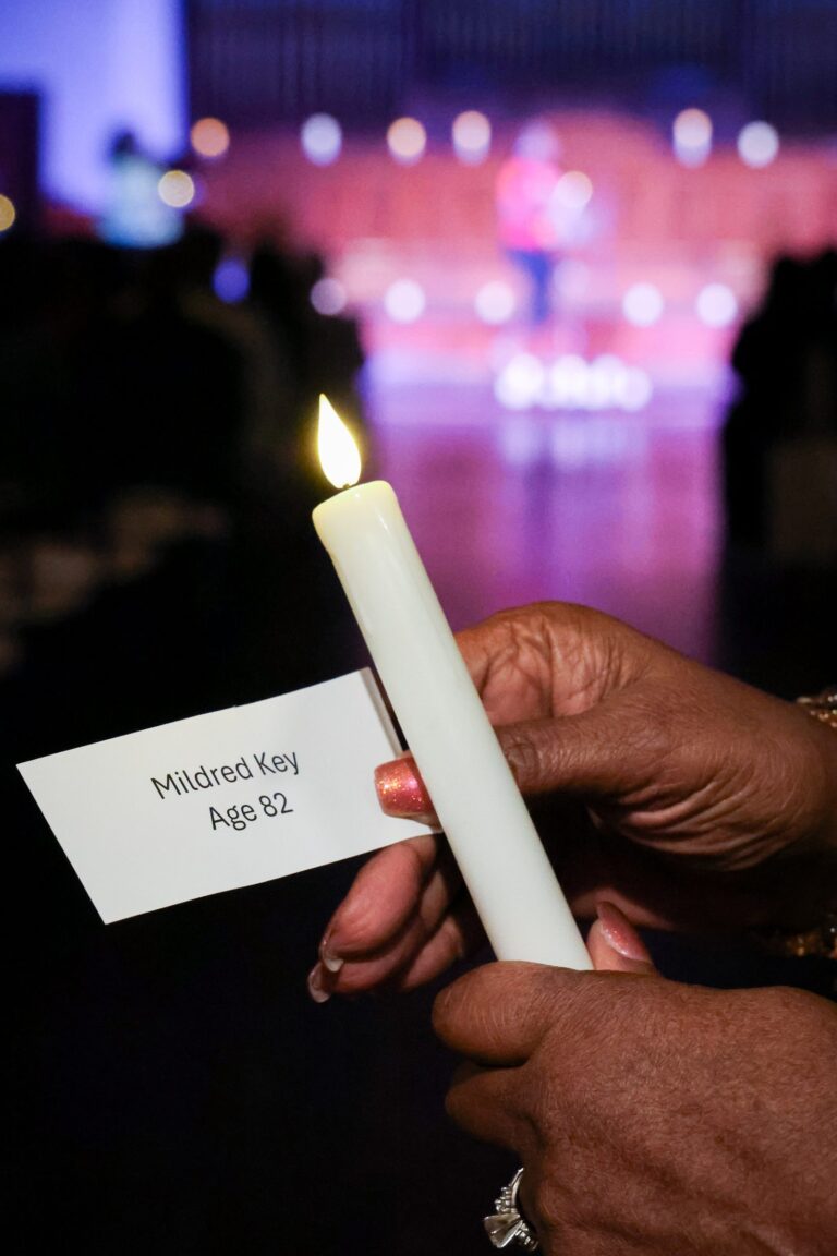 A candle held beside a memorial card during the candle lighting