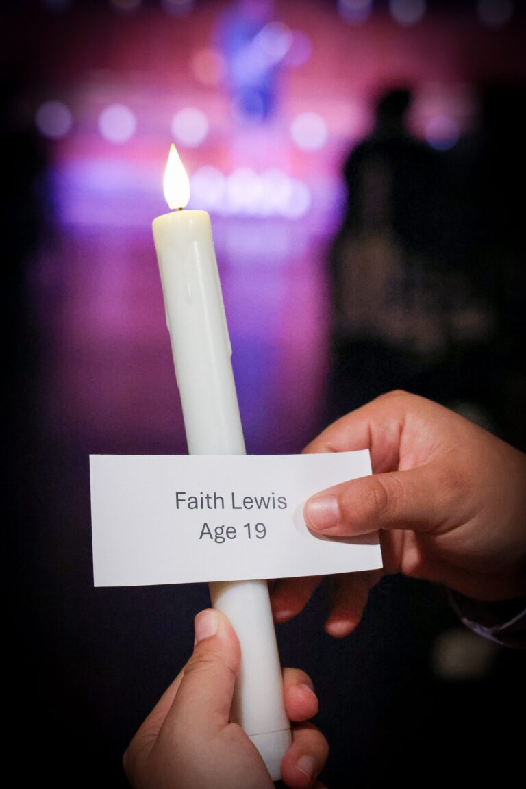 A memorial card held up beside a lit candle