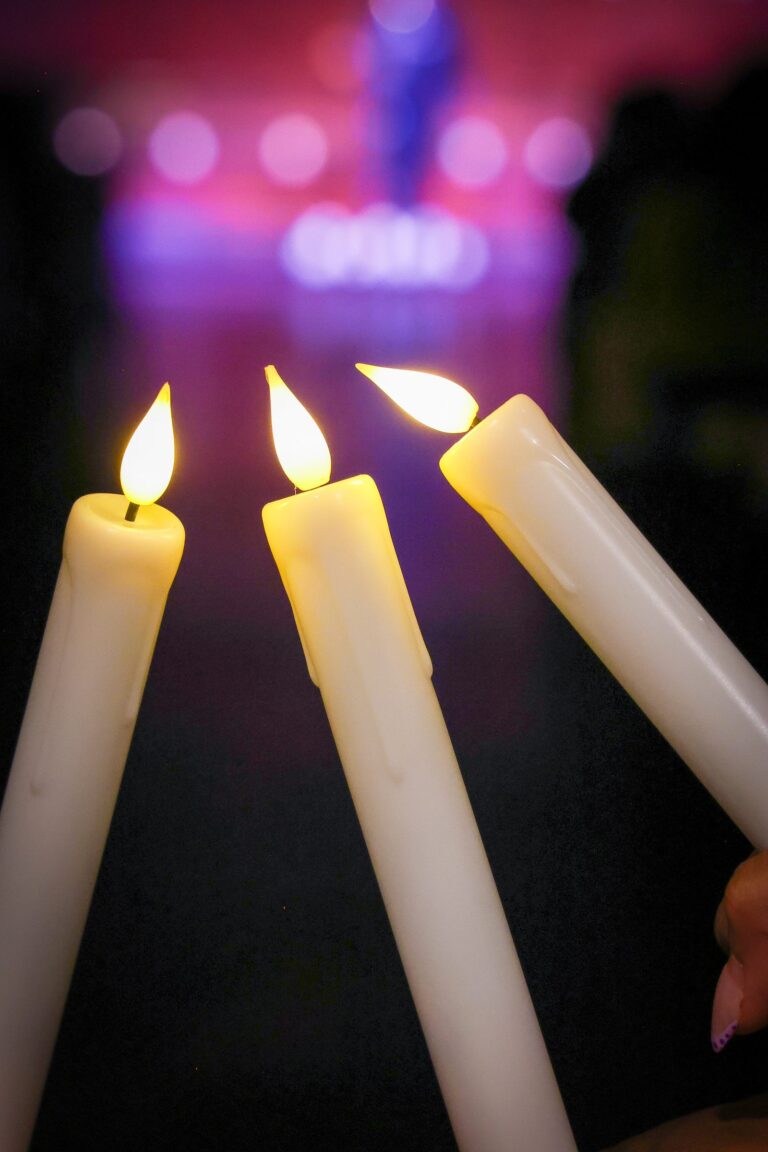 Three candles raised together in the dim sanctuary