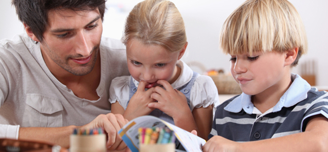 A father reading and drawing with his two children